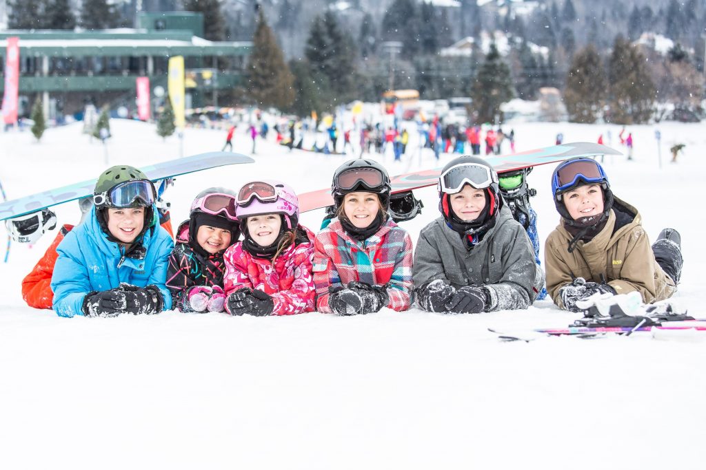 Six enfants couché sur le ventre dans la neige dans une station de ski